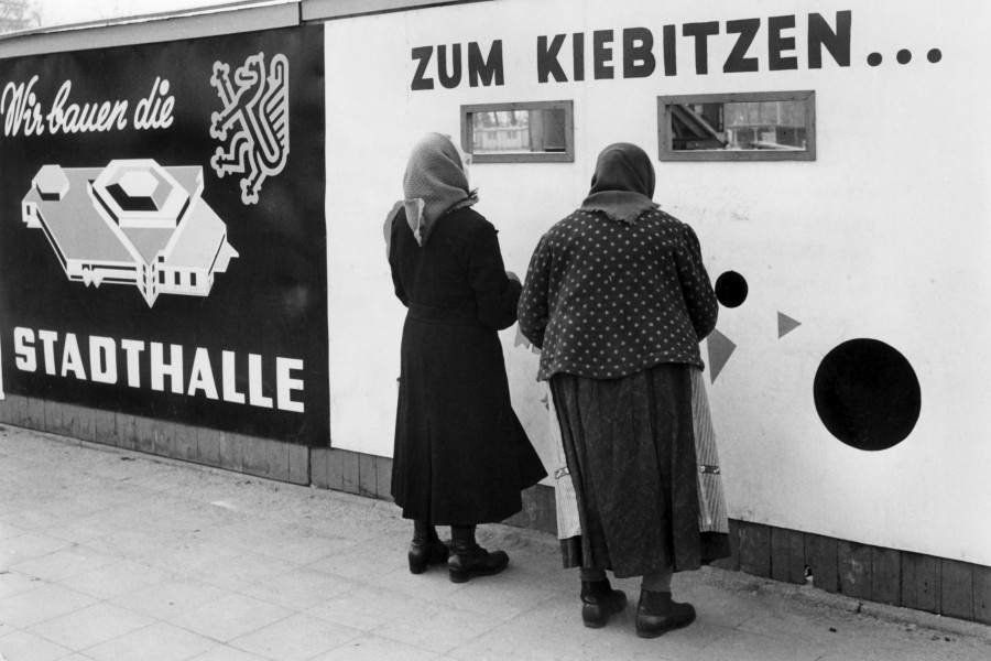 Zwei  Frauen schauen durch Gucklöcher auf die Baustelle der neuen Stadthalle in Braunschweig. Aufnahme vom März 1963.