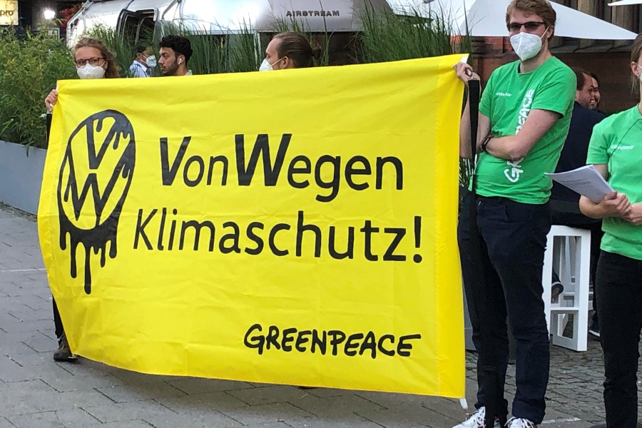Demonstranten von Greenpeace stehen mit einem Poster „VW – Von Wegen Klimaschutz!“ vor einer Halle, in der eine Veranstaltung von Volkswagen stattfand.
