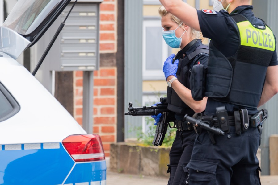 Schwer bewaffnete Polizisten stehen in der Nähe vom Amtsgericht Celle vor dem Kofferraum ihres Autos. 