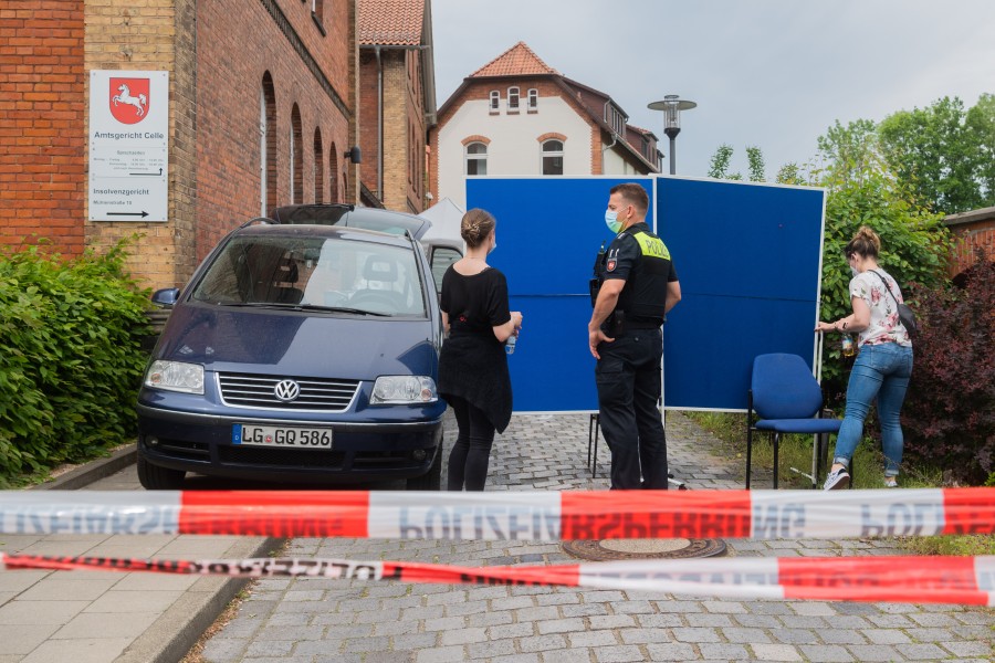 Polizisten stehen im Eingangsbereich des Amtsgerichts Celle, der durch blaue Tafel verdeckt wird. Auf dem Gelände des Amtsgerichts hat ein Mann eine Frau und anschließend sich selbst erschossen. 