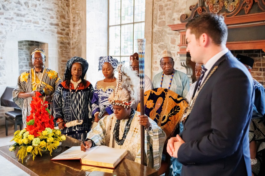 Asabaton Fontem Njifua (M), König höchsten Grades von Fontem aus Kamerun, sitzt mit dem Zeremonialstab in seiner Hand im Altstadtrathaus und trägt sich in das goldene Buch der Stadt Braunschweig ein. 