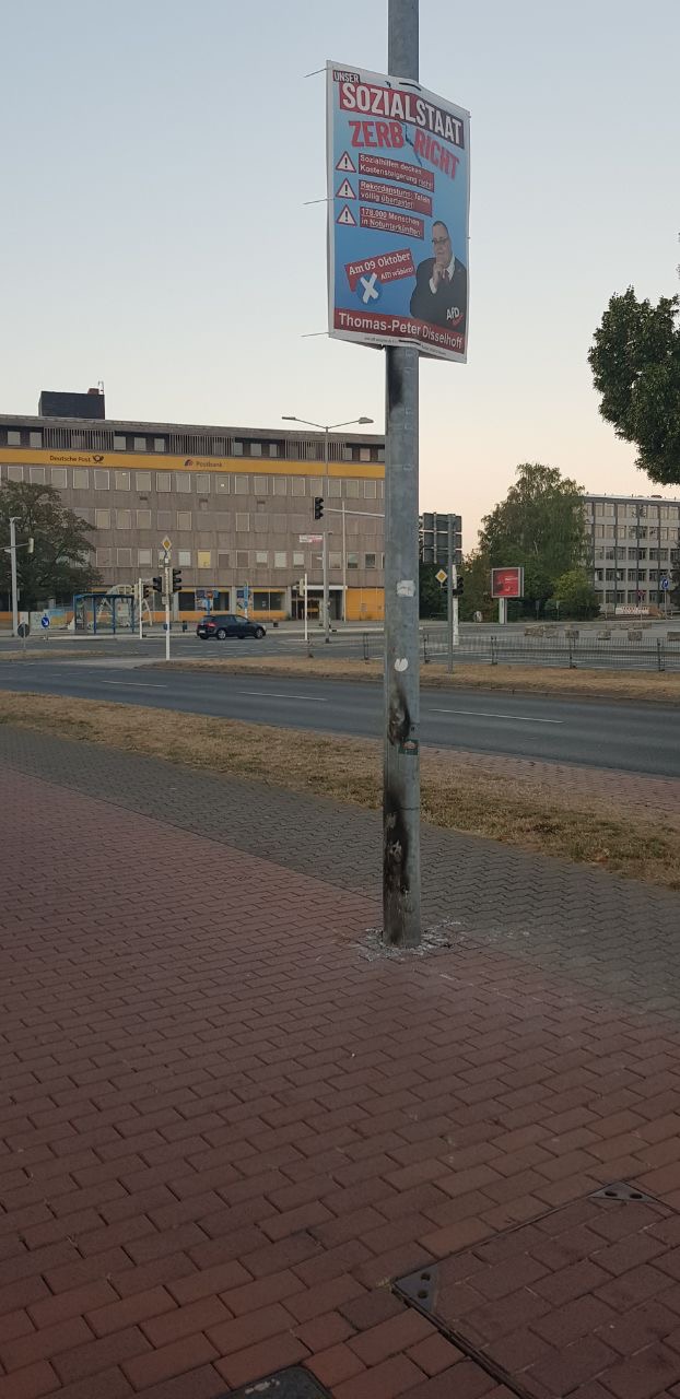 Abgebranntes Parteiplakat steht gegenüber vorm Rathaus