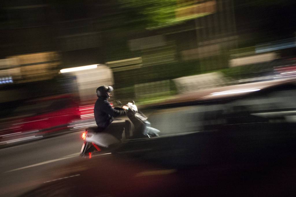 Motorroller fährt durch dunkle Straße