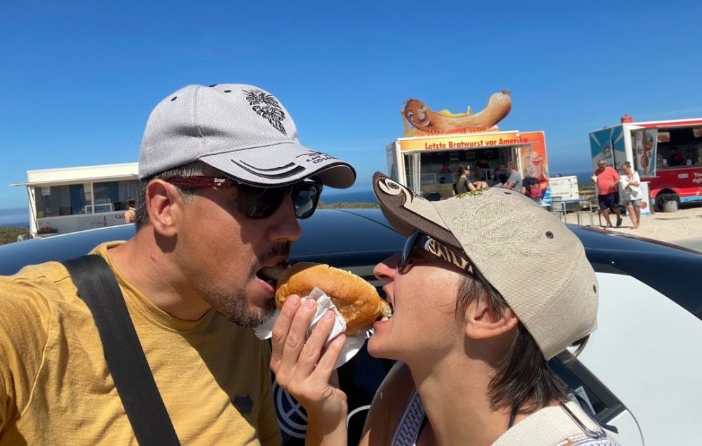 Marc und seine Freundin beißen in die Bratwurst im Brötchen