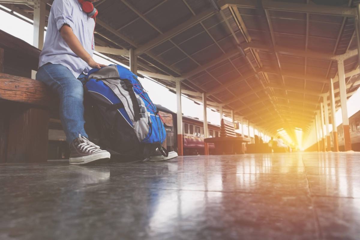 Mann mit Rucksack am Bahnhof