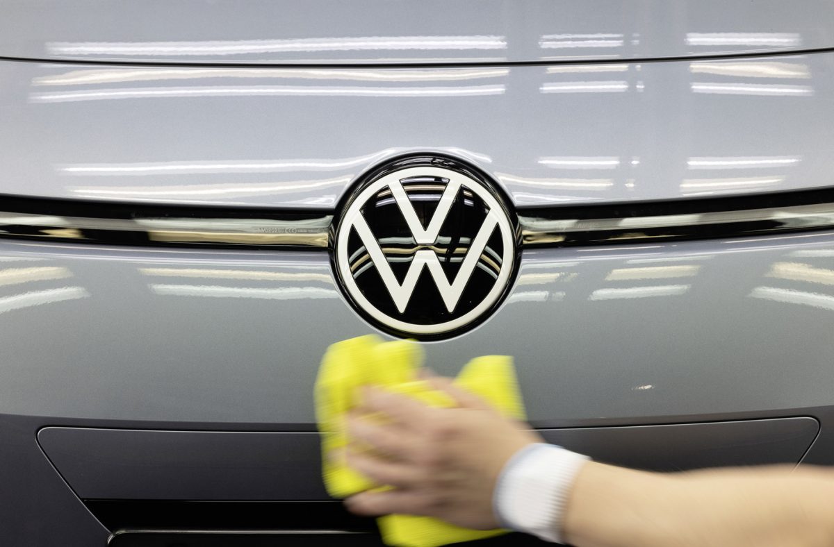 Person wischt mit einem Tuch über VW Logo am ID.3