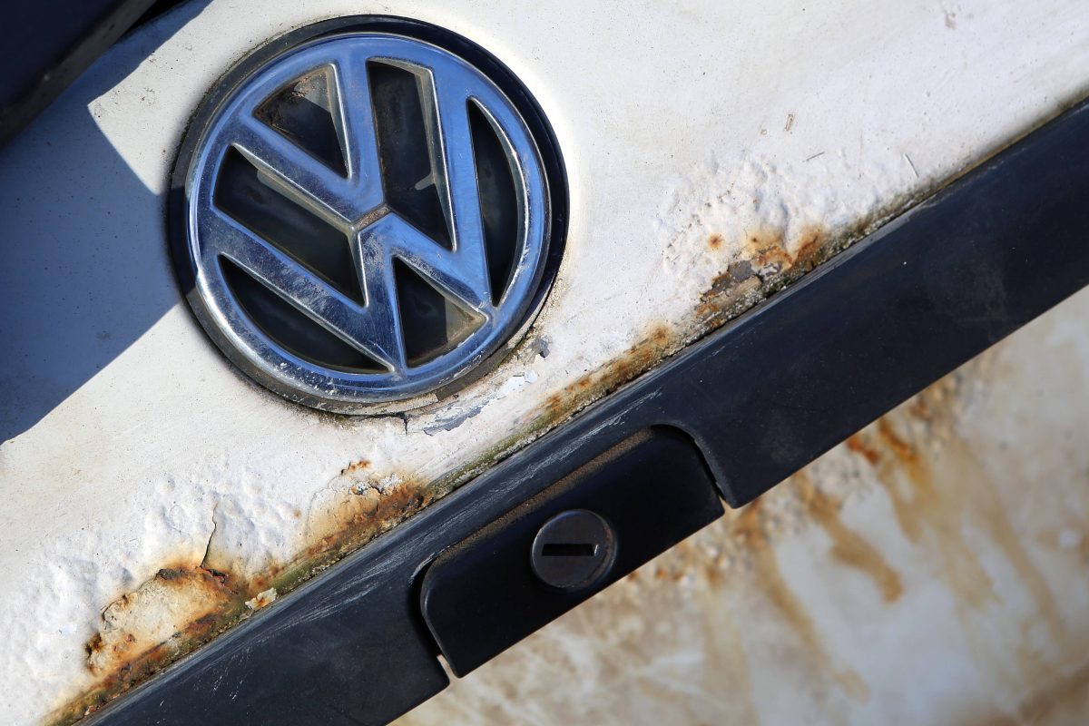 Ein Volkswagen Logo auf dem verrosteten Heck eines alten Golf.