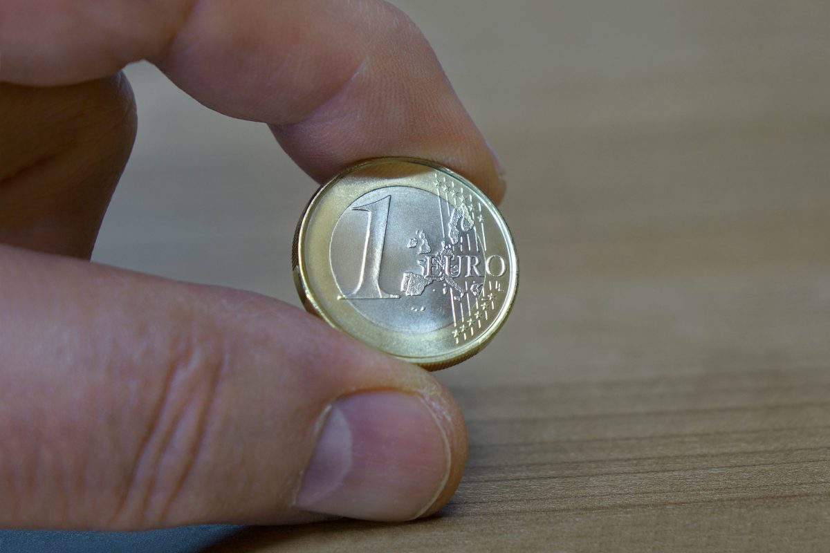Mann hält 1-Euro-Münze in der Hand