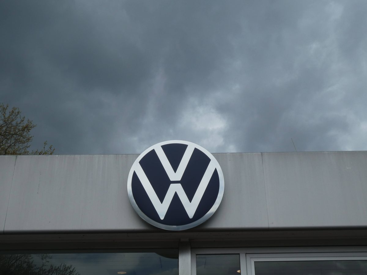 VW Logo an Hauswand dunkle Wolken im Hintergrund