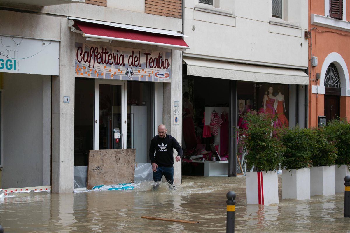 Mann steht in Italien in Einkaufsstraße knietief im Wasser