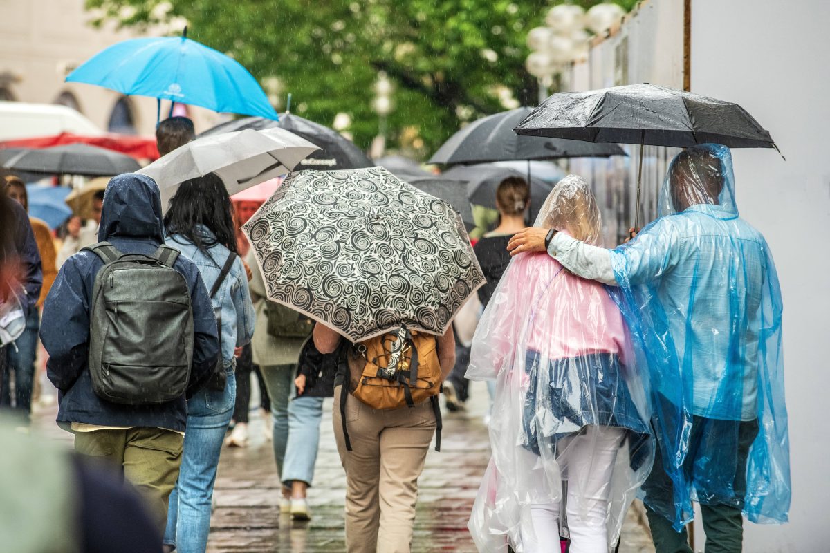 Passanten sind mit Regenschirmen unterwegs