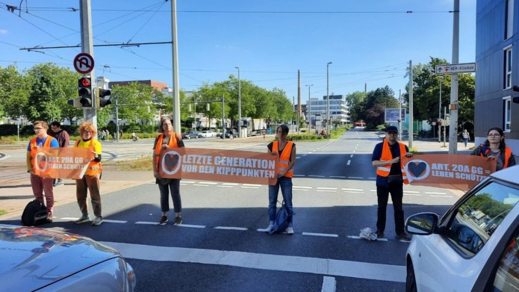 Aktivisten der letzten Generation stehen auf einer Straße in Braunschweig und blockieren den Verkehr