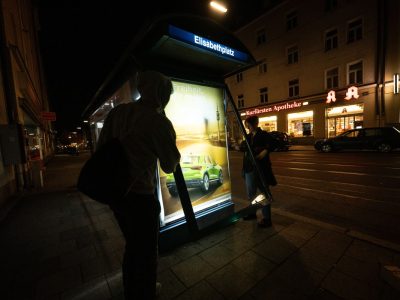 Aktivisten der Nichtregierungsorganisation Attac bringen als Protest gegen die aktuell in München laufende Messe IAA Mobility kritische Persiflagen von Autowerbung an einem Trambahnhäuschen an.