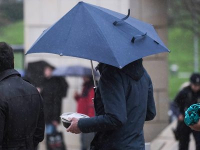 Wetter in Niedersachsen Frau geht bei Sturm mit dem Schirm durch den Regen