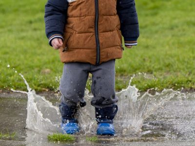 Kind steht in Regenpfütze
