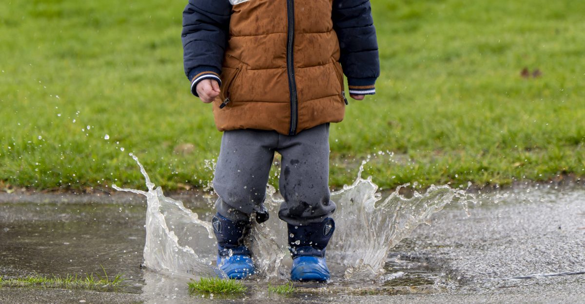 Kind steht in Regenpfütze