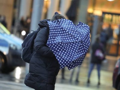 Wetter in Niedersachsen Frau mit Regenschirm geht durch Sturm