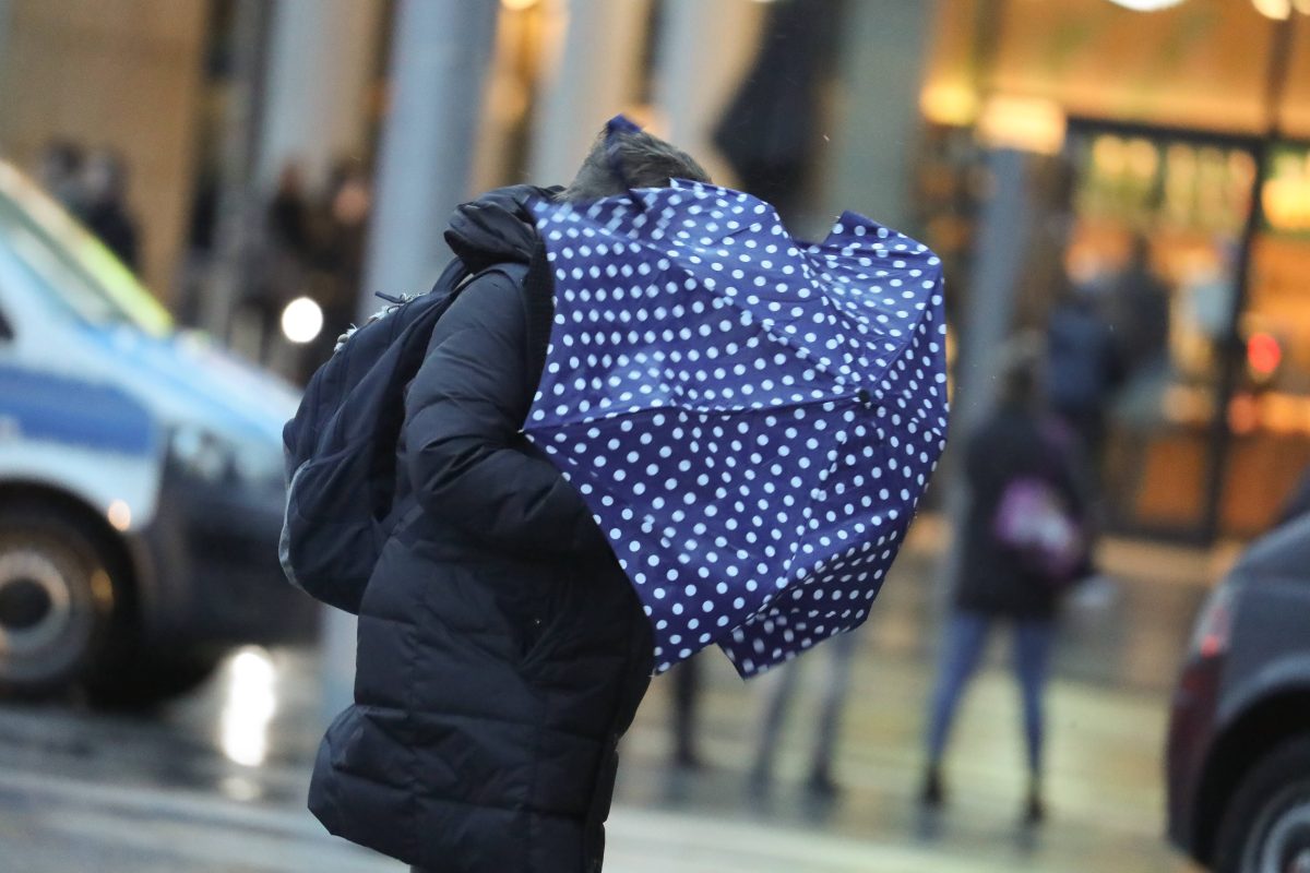 Wetter in Niedersachsen Frau mit Regenschirm geht durch Sturm
