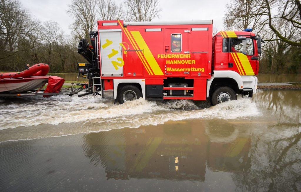 Einsatzkräfte der Wasserrettung der Feuerwehr Hannover fahren über eine überflutete Straße bei Hannover.