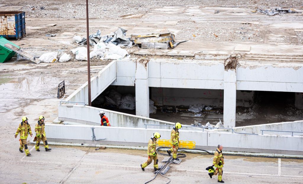 Einsatzkräfte der Feuerwehr gehen über das Gelände einer Großbaustelle im Stadtteil Mitte. Ein Bauarbeiter ist auf der Baustelle von einer Betonplatte verschüttet worden.