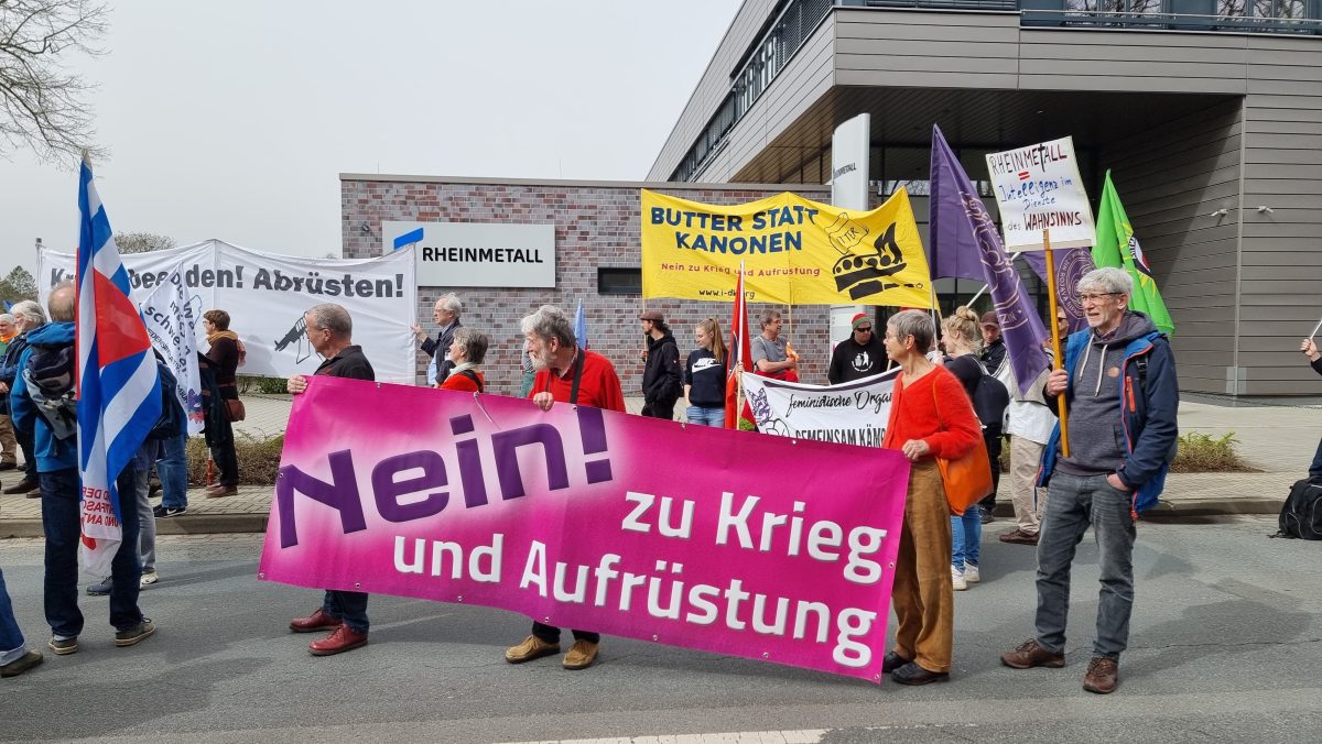 "Nein! zu Krieg und Aufrüstung" steht auf einem Banner von Teilnehmern eines Ostermarsches, die vor dem Gelände des Rüstungskonzerns Rheinmetall in Unterlüß im Landkreis Celle demonstrieren.