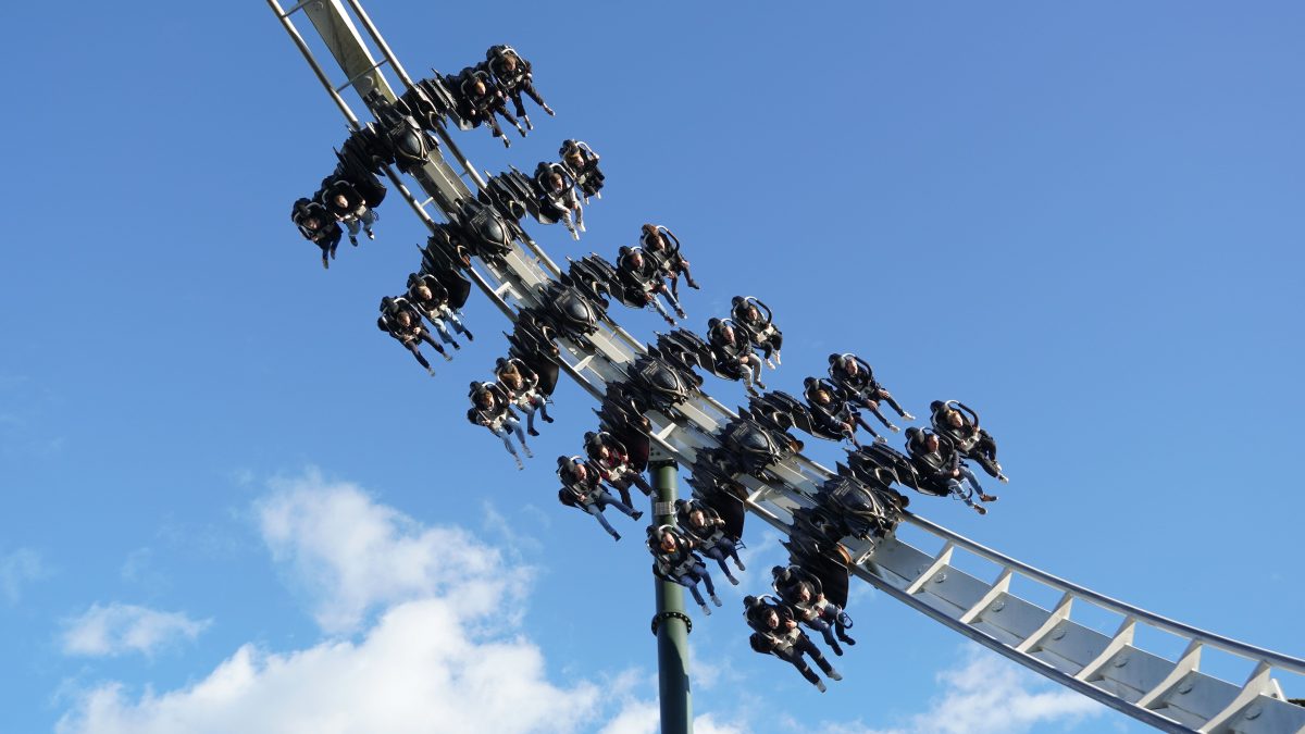 Mehrere Menschen haben Spaß auf einem Fahrgeschäft im Heide Park bei blauem Himmel (Symbolbild)